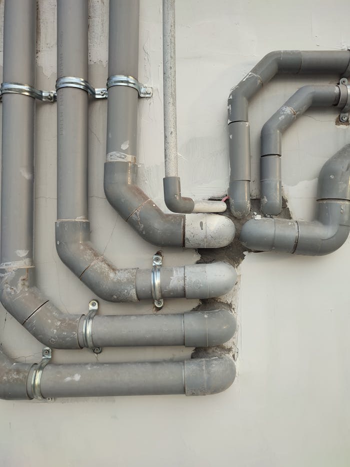 Close-up of interconnected gray metal pipes on an outdoor wall showcasing industrial design.