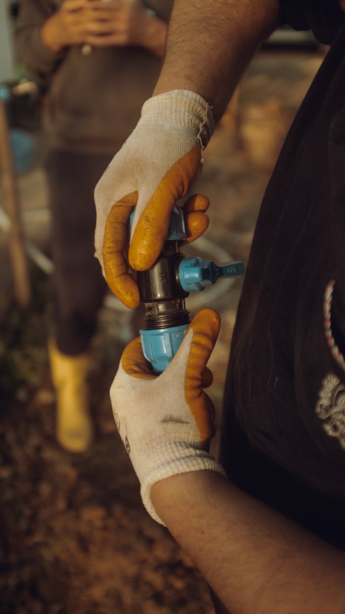 Close-up of a construction worker's hands in gloves assembling a water pipe outdoors in Kandıra, Turkey.